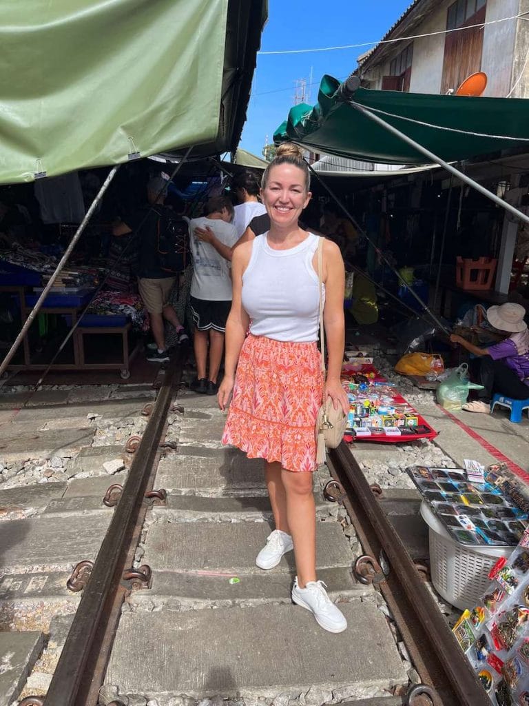 A photo of a traveler standing on the tracks of the Maeklong Railway Market on Go Ahead Tours Thailand for Solo Travelers.