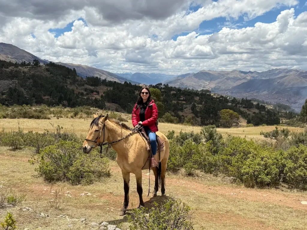 An image of a tourist horseback riding through hidden temples in Cusco Peru