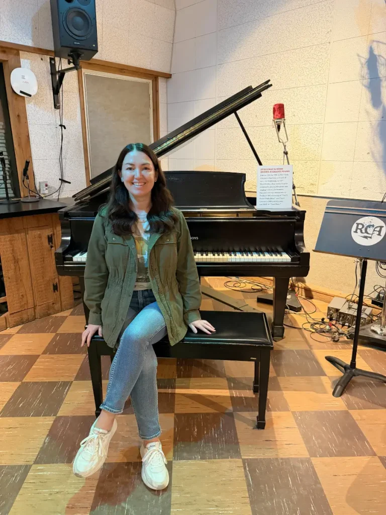 Visitor posing at Elvis Presley's Steinway piano inside RCA Studio B in Nashville, Tennessee.
