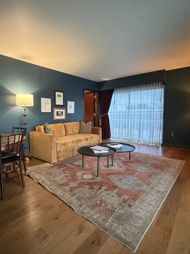 Living area inside the Chalet Suite at the Hotel Chalet Chattanooga Tennessee, featuring a pullout sofa, dining table, and floor-to-ceiling windows.