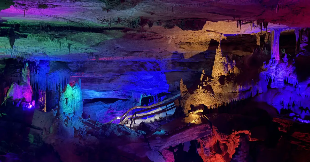 Colorful cave formations illuminated by multicolored lights during the Crystal Palace Tour at Raccoon Mountain Caverns in Chattanooga, Tennessee