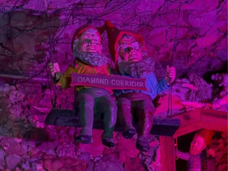 Glowing gnome figures inside Fairyland Caverns at Rock City Gardens, illuminated by colorful black lights and glow-in-the-dark displays.