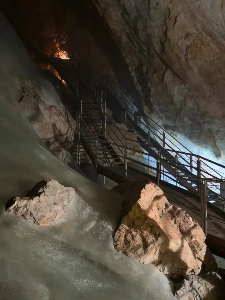 Steep metal staircases winding between ice formations and limestone walls inside Eisriesenwelt Ice Cave.