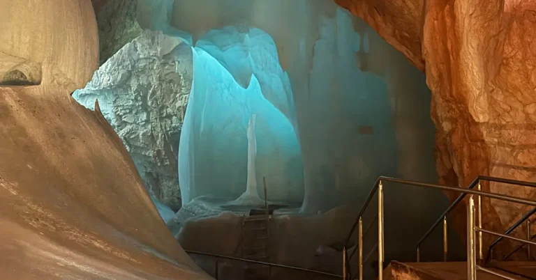 Blue ice formations surrounded by limestone walls and metal stair railings inside Eisriesenwelt Ice Cave in Werfen, Austria.