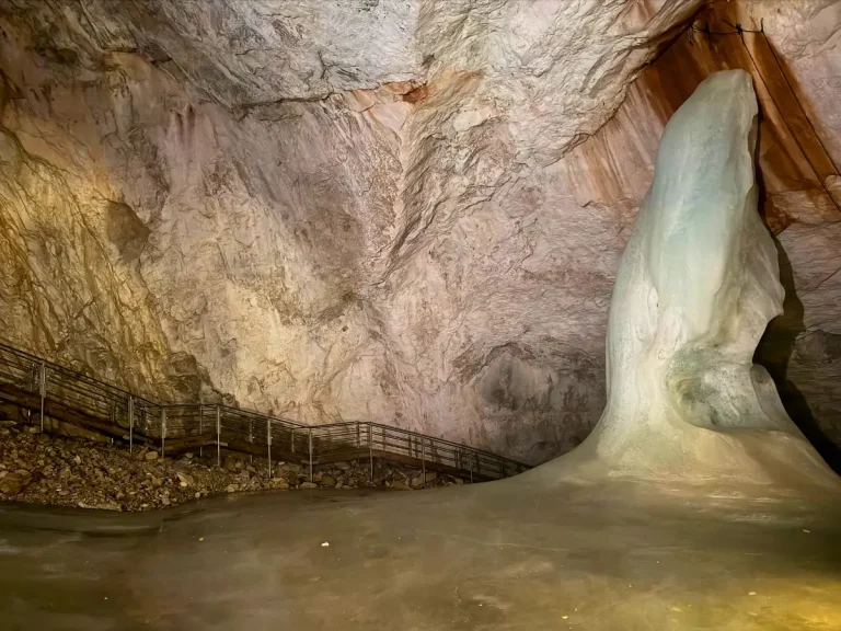 Towering ice formation known as Posseltturm (Posselt Tower) beside metal staircases inside Eisriesenwelt Ice Cave in Austria.
