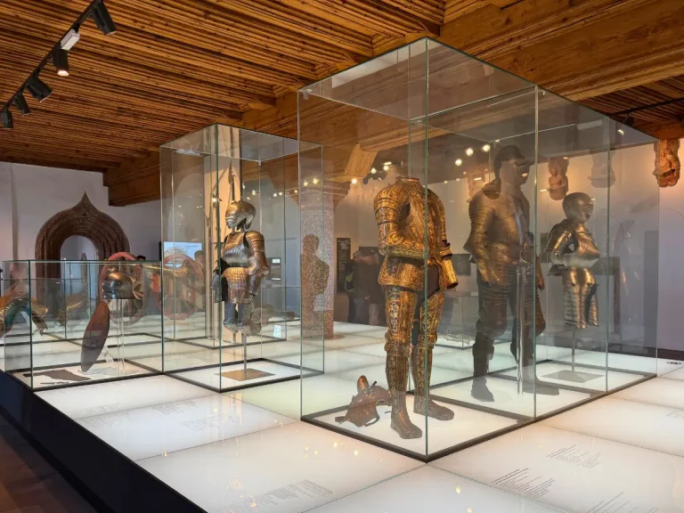 Historic suits of armor and helmets displayed in glass cases inside the Fortress Museum at Hohensalzburg Fortress.