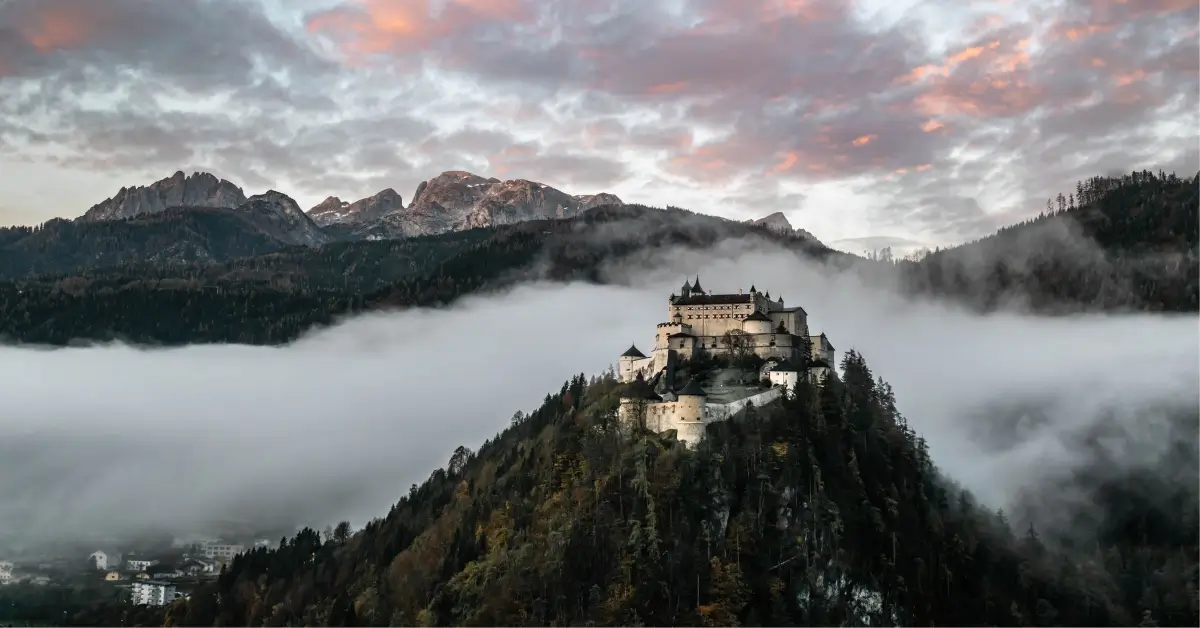 Hohenwerfen Fortress rising above a valley filled with fog, surrounded by the Austrian Alps near Werfen, Austria.